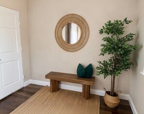Ein Zimmer mit einer hölzernen Sitzbank, einem runden Spiegel und einem Blumentopf.