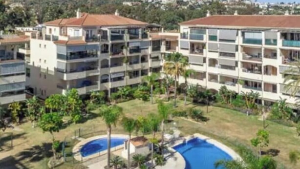 Un hotel de varios pisos con balcones, piscina y jardín ajardinado.