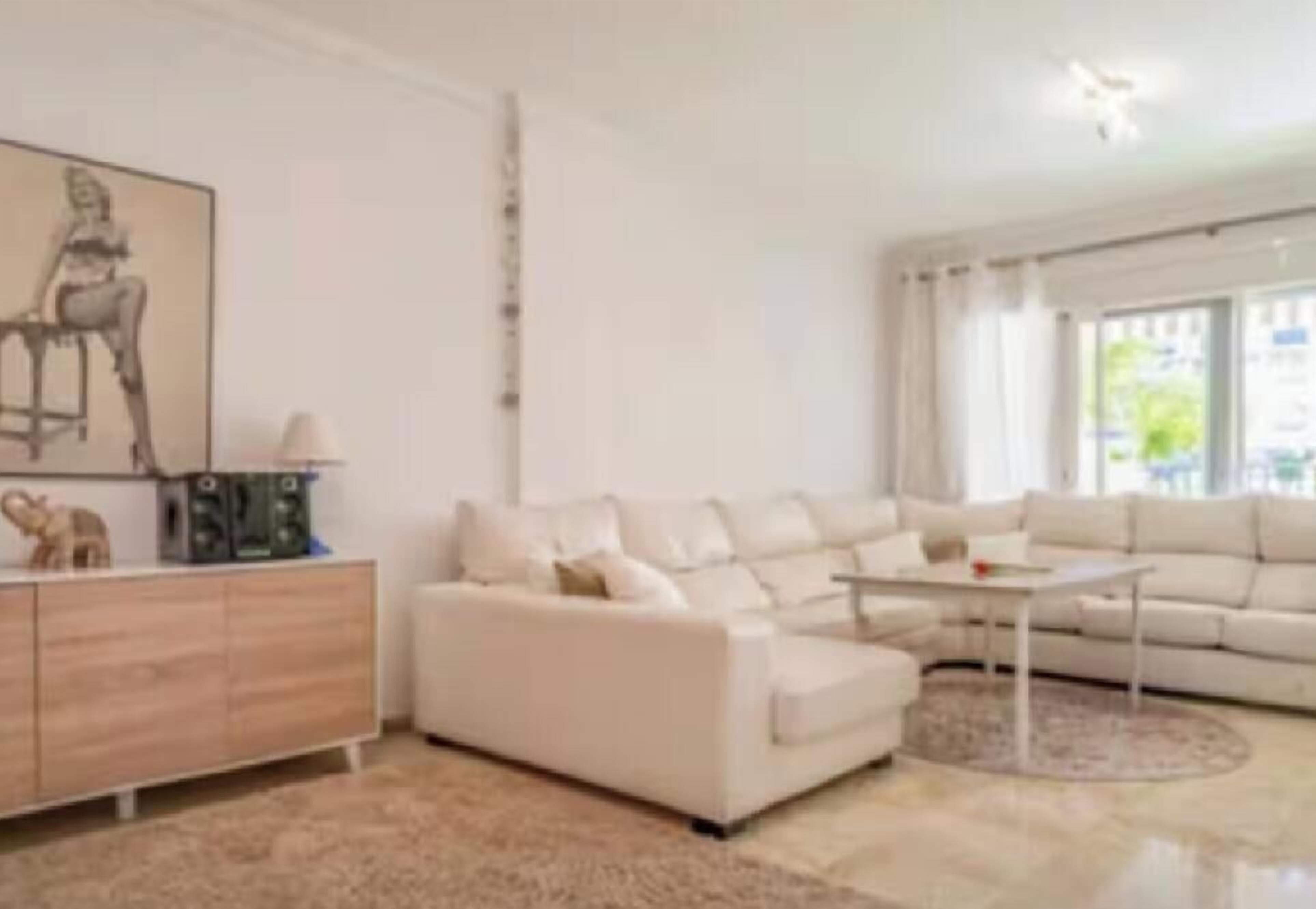 A modern living room with a white sofa, a coffee table, and a sideboard.