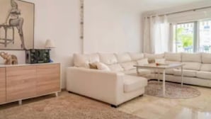 Una sala de estar moderna con un sofá blanco, una mesa de centro y un aparador.