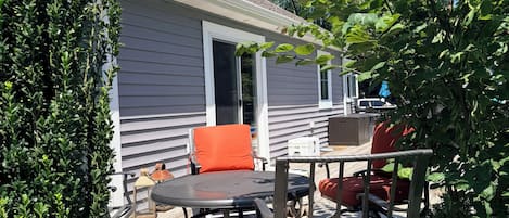 Eine Terrasse mit Gartenmöbeln, einem Topfpflanzen und einem Haus im Hintergrund.