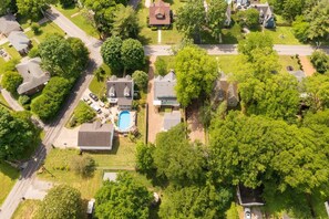 An aerial view of a residential area with houses, a swimming pool, and surrounding greenery. - The Storybook Stay / Woodson Historic District (Gallatin)
