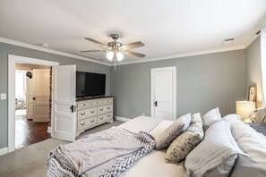 Ein Schlafzimmer mit einem Bett, einem Schminktisch, einem Deckenventilator und einem Fernseher.