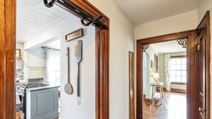 A hallway with a wooden door, a measuring tape, and a kitchen area with a stove and cabinets.
