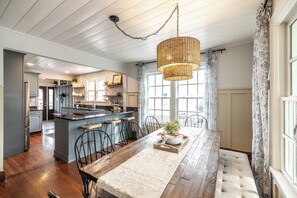 A kitchen with a central island, wooden chairs, a dining table, and a hanging light fixture. - The Storybook Stay / Woodson Historic District (Gallatin)