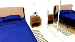 A bedroom with two beds, a nightstand, a mirror, and a small plant. - Apartment in Punta Centinela Townhouse 200 (Santa Elena)