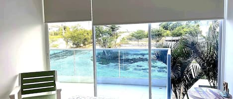 Un dormitorio con cama, una silla y vistas a una piscina y zonas verdes.