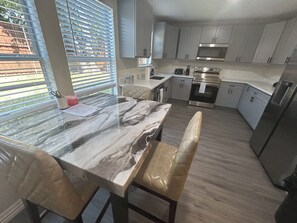 Eine moderne Küche mit Marmorarbeitsplatte, Edelstahlgeräten und hellem Holzboden.