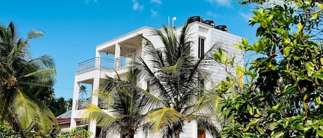 A two-story building with a balcony, surrounded by a well-maintained lawn and palm trees.