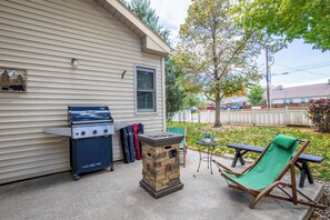 A backyard with a barbecue grill, a stone fire pit, and a green lawn chair. - Modern, pet-friendly Retreat near everything! (Montrose)