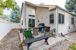 Une maison de plain-pied dotée d’un patio, d’un barbecue et de meubles de jardin.
