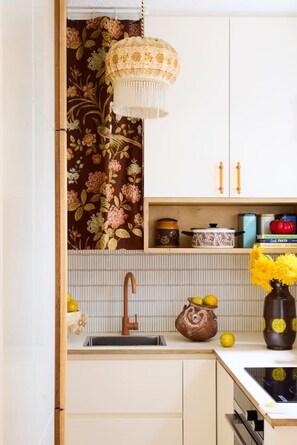 A kitchen with a white cabinet, a brown faucet, and a hanging light fixture. - Retro Bronte Beach Pad | 4 Min Walk to Beach (Bronte)