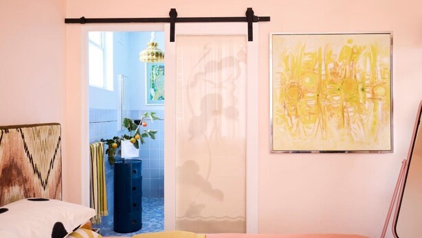 Une chambre à coucher avec un lit, une fenêtre, une porte et un tableau accroché au mur.