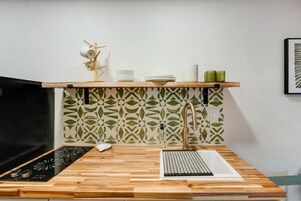 A kitchen with a wooden countertop, a sink, and a backsplash with a leaf pattern.