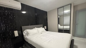 A modern bedroom with a large bed, a nightstand, a mirror, and a wardrobe. - Casa Neeyam: Luxury & space, 7 min from airport. 3BR/2BA, AC, Wi-Fi, parking (Carolina)