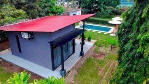 A modern two-story building with a red roof, large windows, and a small patio area.
