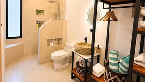 A modern bathroom with a shower, toilet, and sink. There is a wooden shelf with towels and a basket. - Las Brisas Studio - Saltwater Pool (Hojancha)