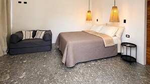 A bedroom with a bed, a sofa, a small table, an air conditioning unit, and pendant lights. - Las Brisas Studio - Saltwater Pool (Hojancha)