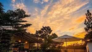 A patio area with a wooden deck, outdoor furniture, and a view of the sunset. - Las Brisas Studio - Saltwater Pool (Hojancha)