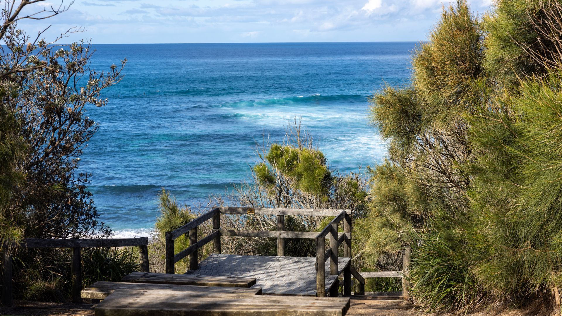 Una escalera de madera que conduce a una playa con vista al océano.