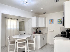 A modern kitchen with white cabinets, a round dining table, and two chairs. - 🌴🍹Cozy Retreat 3BR Near Tampa, Disney, Legoland (Lakeland)