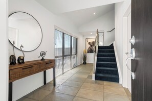 Ein modernes Interieur mit einem Holzkonsolentisch, einem großen Spiegel und einer Treppe, die zu einer oberen Ebene führt.