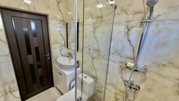 Un baño moderno con ducha de vidrio, inodoro y lavamanos.