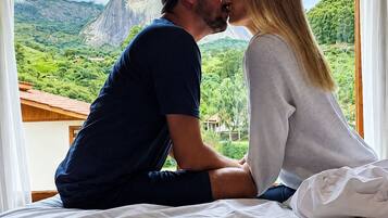 Una pareja sentada en una cama con vistas a un paisaje montañoso.