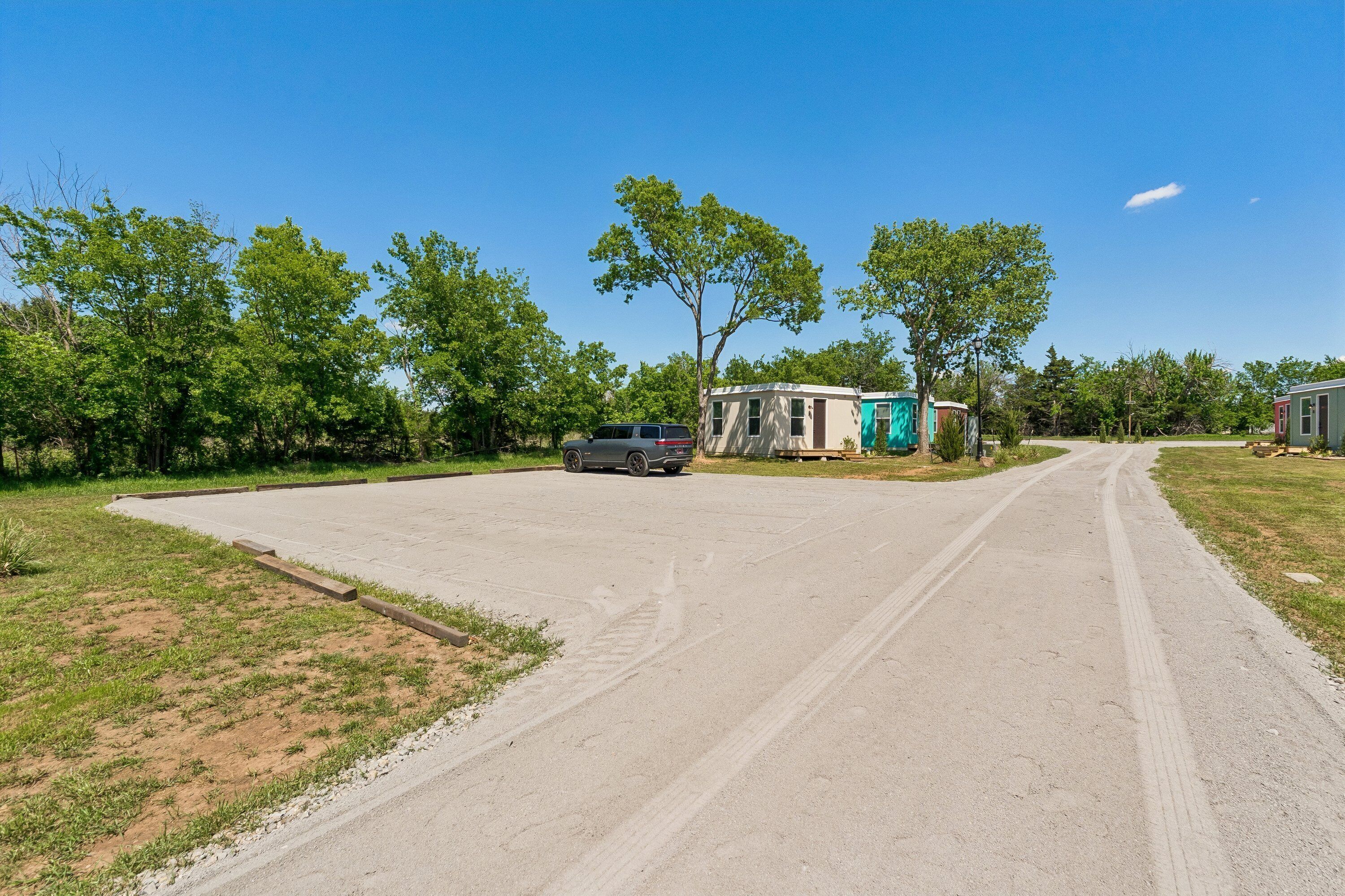 Une allée de gravier mène à une rangée de maisons mobiles, avec une voiture garée devant.