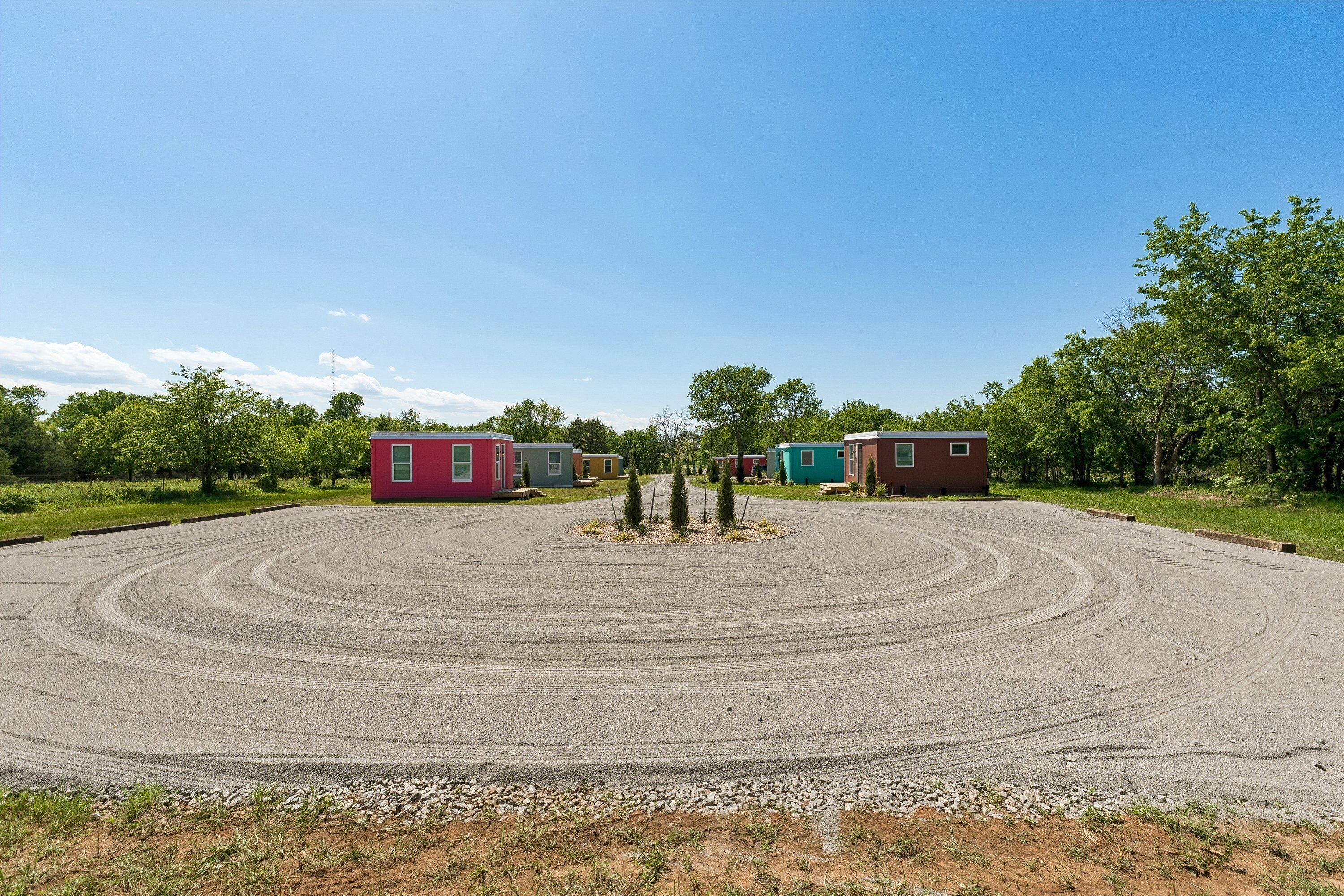 A circular driveway leading to a row of small, colorful cabins.