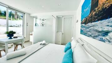Una camera d'albergo moderna con un letto grande, un'area ristoro e vista sul mare.