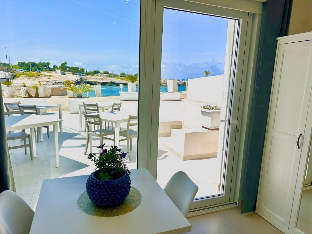 A room with a view of a pool and beach, a dining table with chairs, and a cabinet.