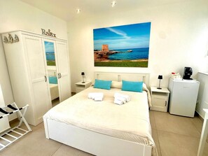A bedroom with a bed, a wardrobe, a painting, a desk, and a refrigerator. - Torre Pozzillo Beach (Pozzillo)