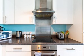 Une cuisine moderne équipée d’une cuisinière intégrée, d’un grille-pain et d’une bouilloire posés sur le plan de travail.