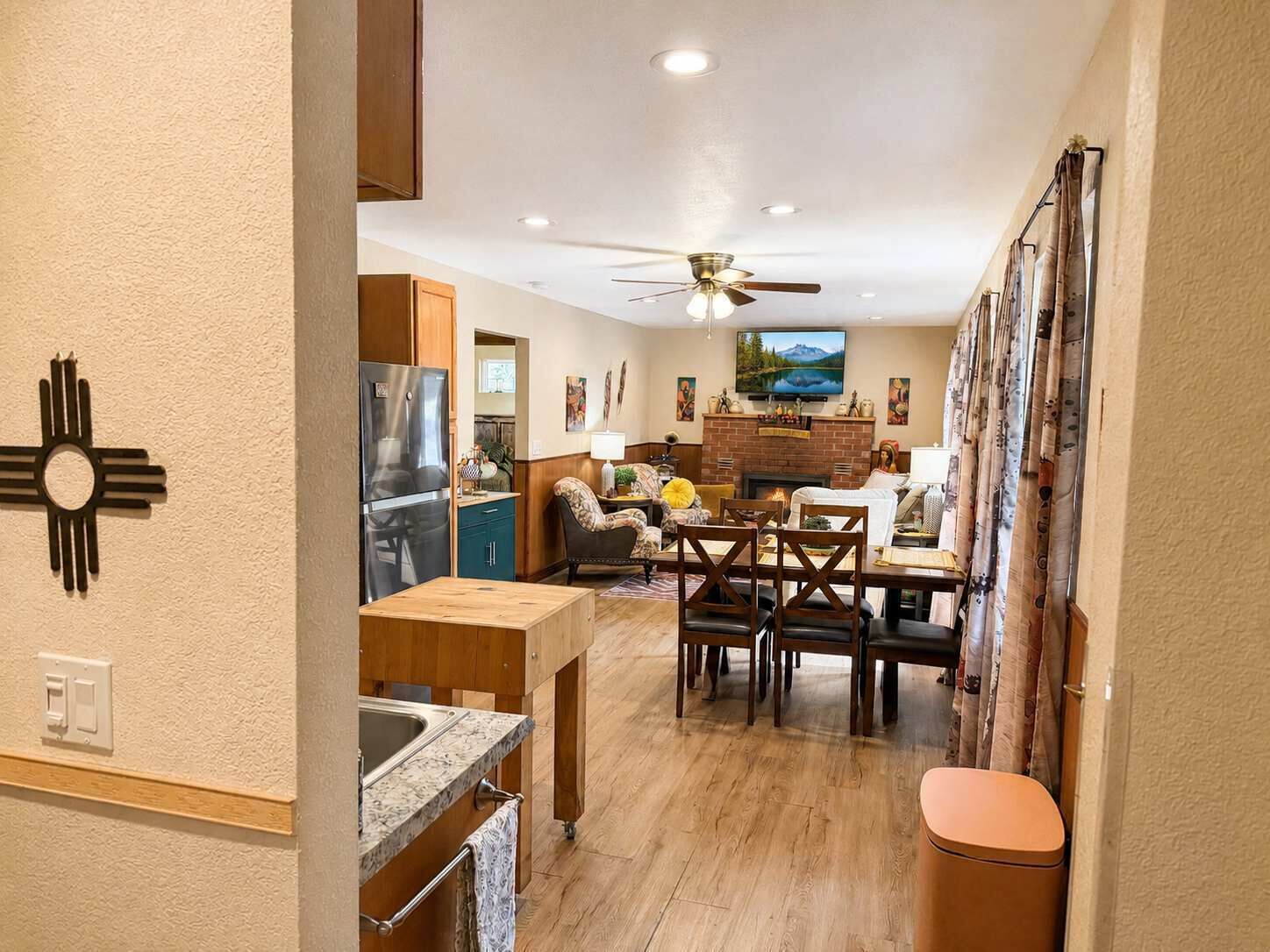 A modern kitchen with a built-in refrigerator, a dining area with a wooden table and chairs, and a fireplace.