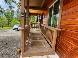 Eine Holzhütte mit Veranda, einer Bank und einem geparkten Auto davor.