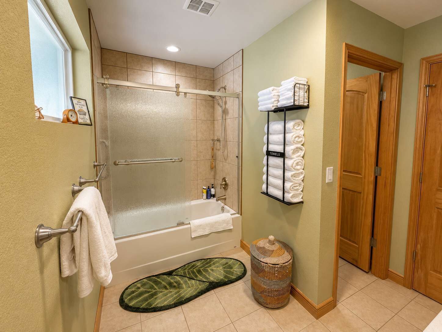 Un baño con bañera, ducha, toallero y cubo de basura.