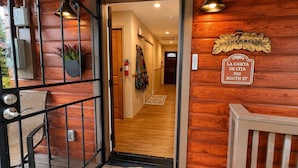 A wooden interior with a welcome sign, a fire extinguisher, and a view into the hallway. - Adorable, easy access, level cabin super clean! (Ruidoso)