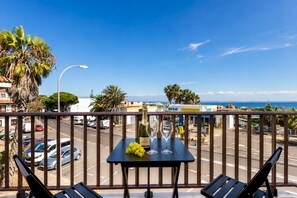 Ein Balkon mit Tisch, zwei Stühlen, einer Weinflasche und einem Glas.