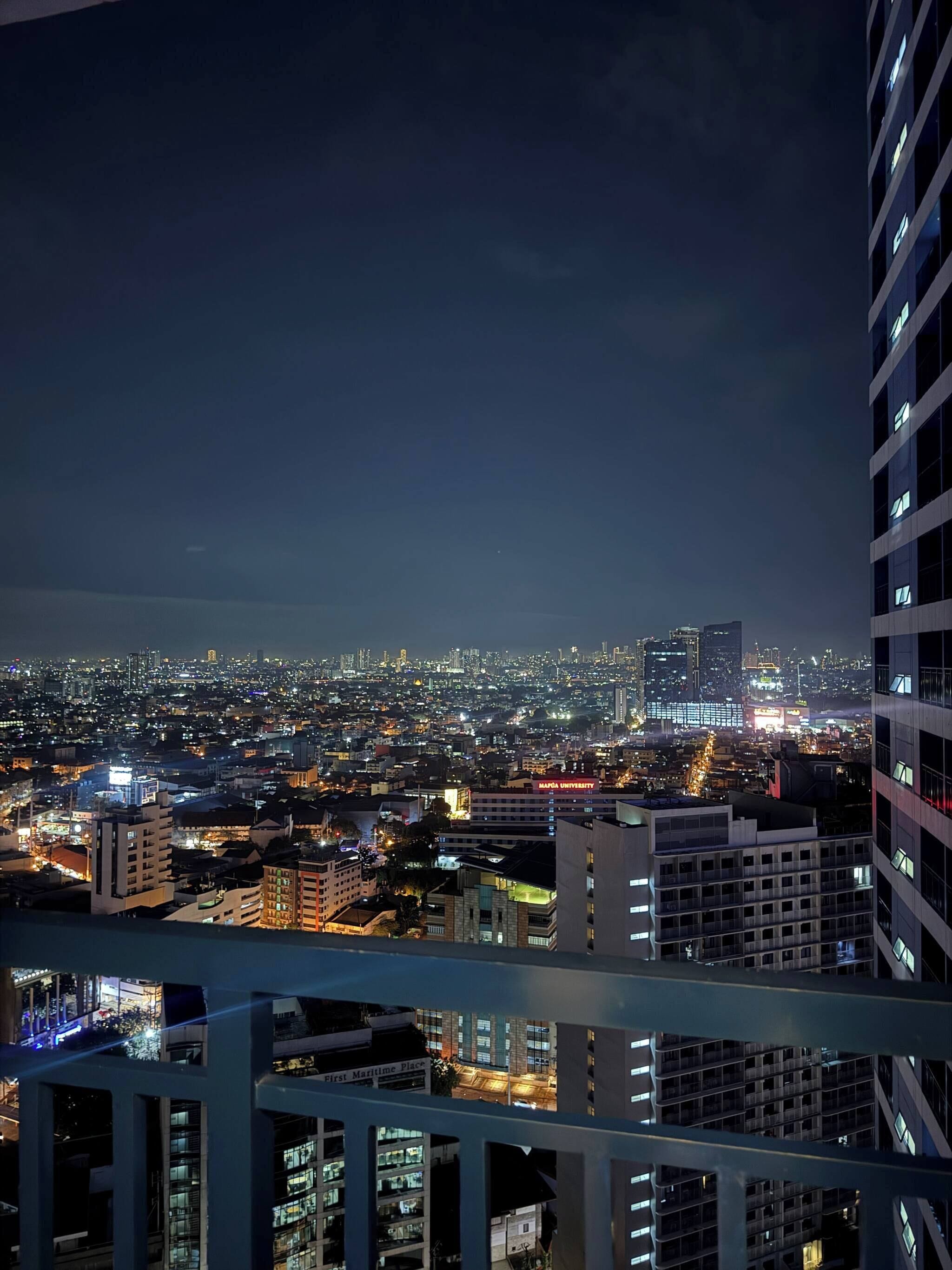 A nighttime cityscape with illuminated buildings and a view of a university campus.