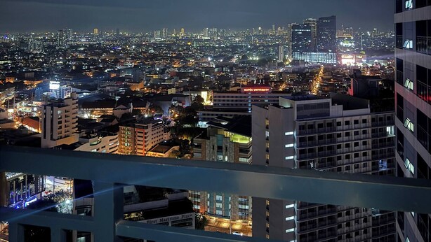 A nighttime cityscape with illuminated buildings and a view of a university campus. - Fully Furnished Makati Condo With Fast Wi-fi and Queen Bed (Makati)