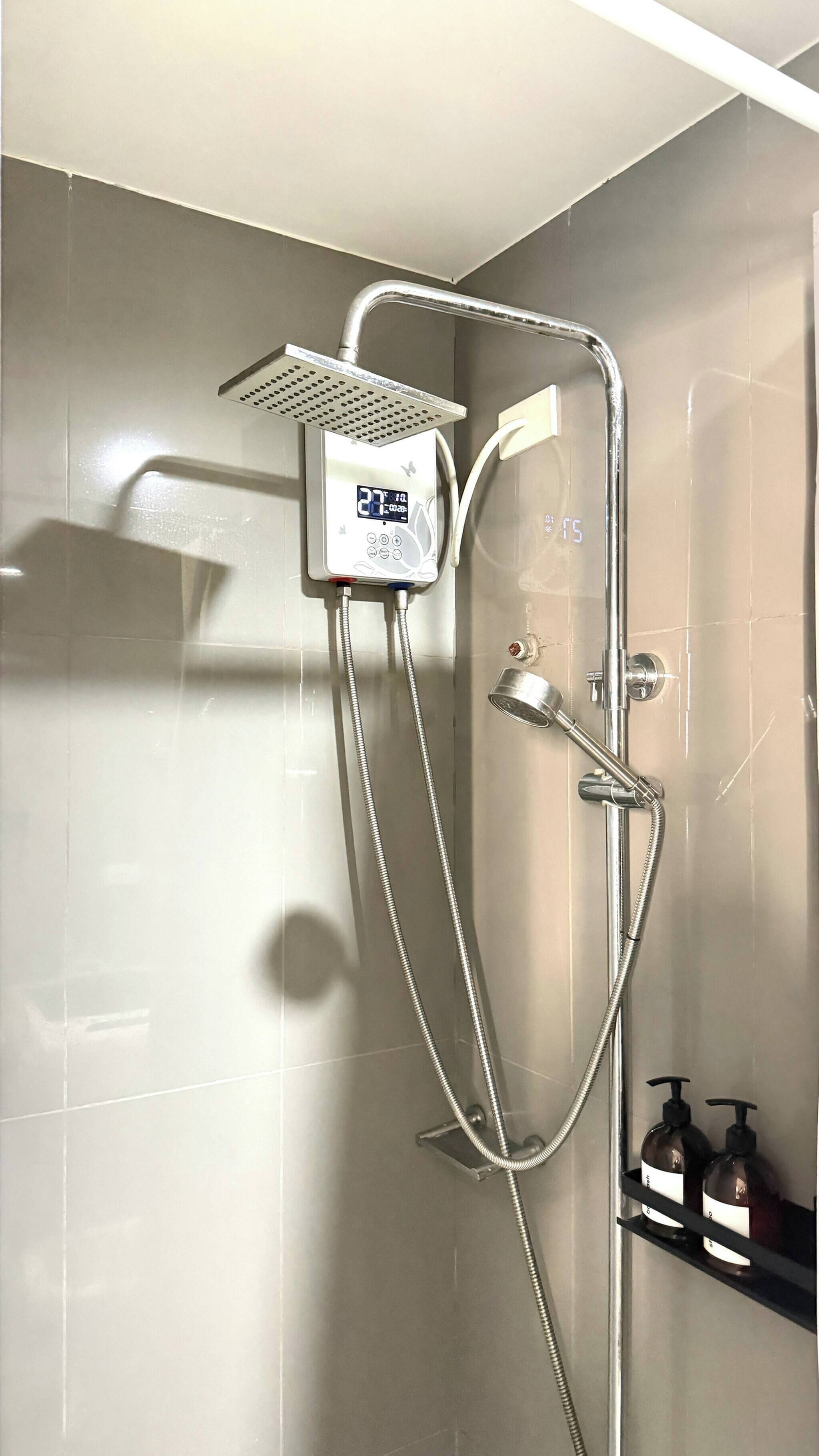 A modern shower with a digital control panel, a handheld showerhead, and a wall-mounted faucet.