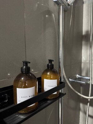 Un bagno con doccia e due flaconi di bagnoschiuma su uno scaffale.
