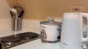 A kitchen with a stove, a slow cooker, and a coffee maker. - Fully Furnished Makati Condo With Fast Wi-fi and Queen Bed (Makati)