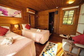 Una cabaña de madera con dos camas, una mesita y una silla.