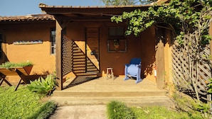 Un porche de madera con un banco, un taburete y una silla.