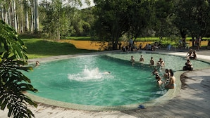 Una piscina rodeada por un muelle de madera, con gente nadando y descansando.
