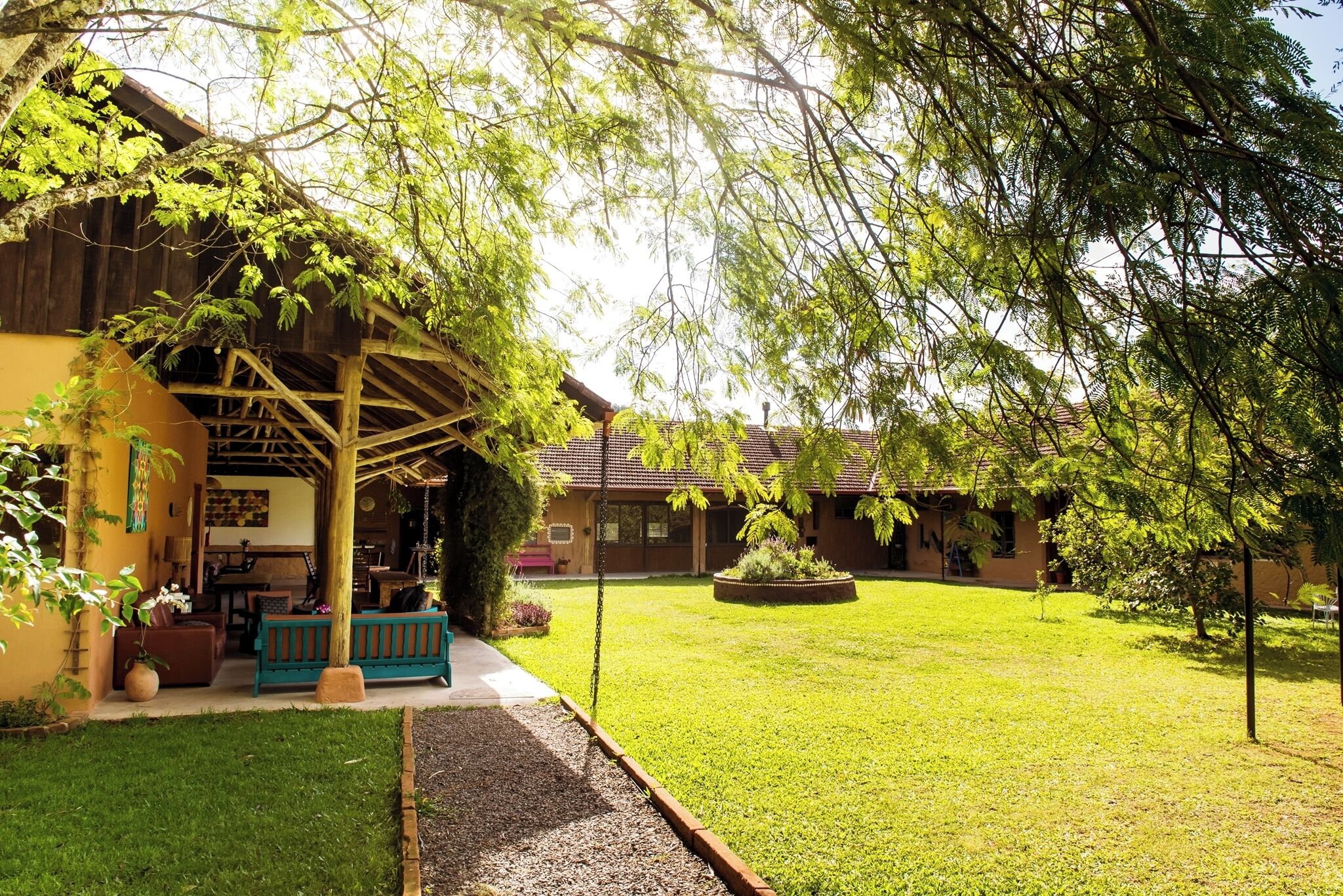 Un edificio con un patio coperto, un prato e un piccolo giardino.