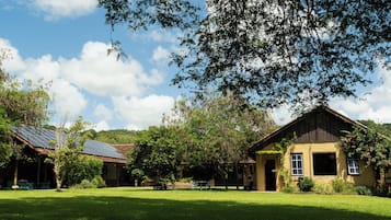 Uma propriedade rural com um amplo gramado, um edifício de madeira e um conjunto de painéis solares.