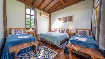 Quarto com duas camas, teto de madeira, janela e tapete colorido.